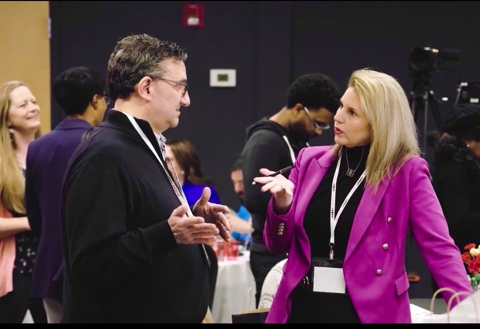 Laura in focused one-on-one conversation with a leader at an event