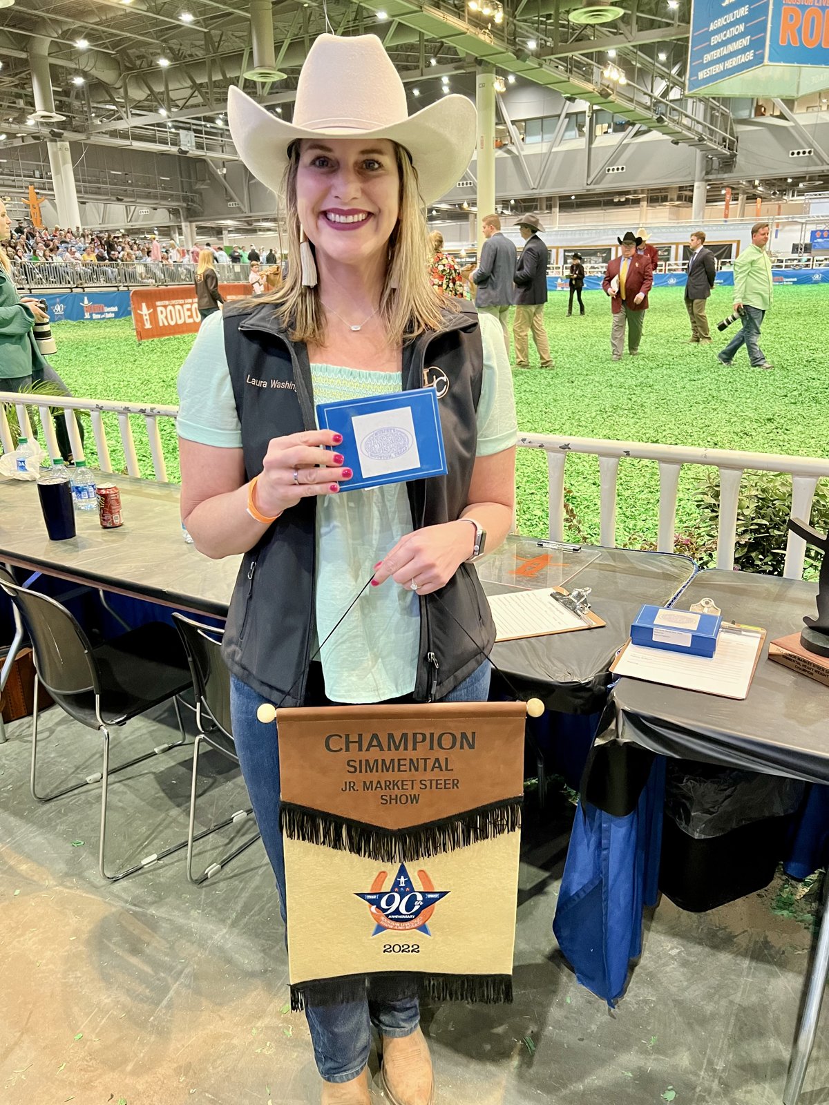 Laura in a cowboy hat with a Champion Simmental banner at the Houston Livestock Show & Rodeo